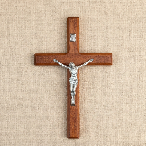Hand-carved wooden wall cross photographed from above on linen