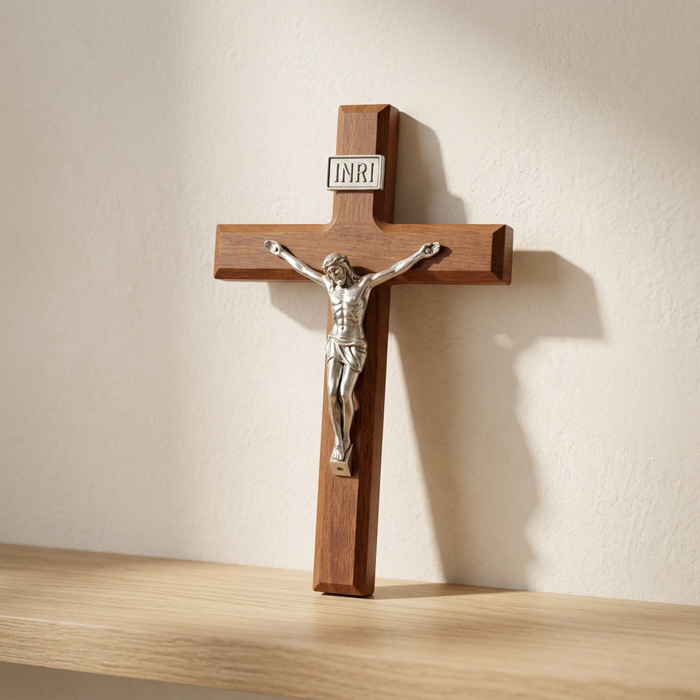 Hand-carved wooden wall cross propped against a plaster wall