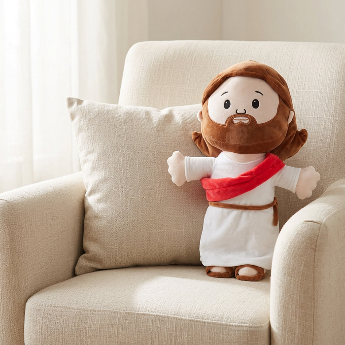 Jesus hug plush in the 50cm size on the same armchair, shown beside a cushion for scale